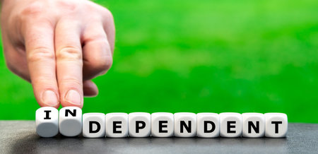 Hand turns dice and changes the word "dependent" to "independent".の写真素材