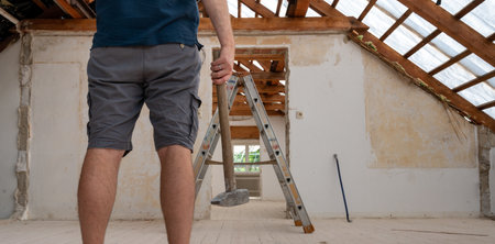 Construction worker with a hammer during the renovation of the attic of a house.の写真素材