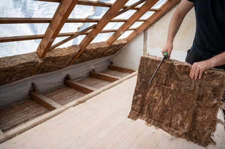 Craftsman cutting insulation material to insulate the attic.の写真素材