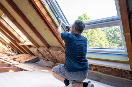 Craftsman caulking a new window in the attic.の写真素材