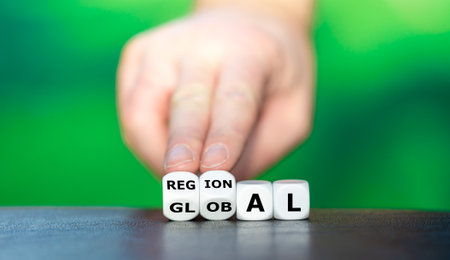 Hand turns dice and changes the word global to regional.の写真素材