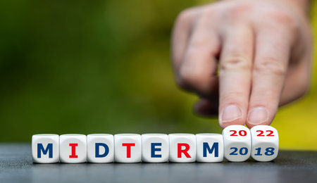 Symbol for the mid-term election 2022 in the United States. Hand turns dice and changes the...