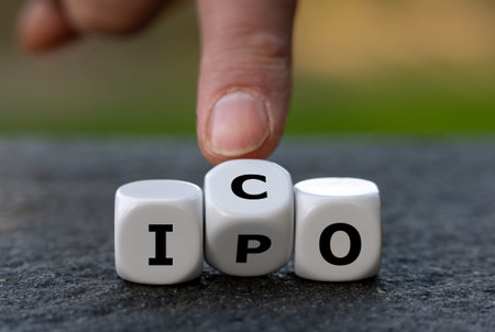 Hand turns dice and changes the abbreviation IPO (initial public offering) to ICO (initial coin...