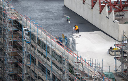 Roofer painting flat roof of a commercial building.の写真素材