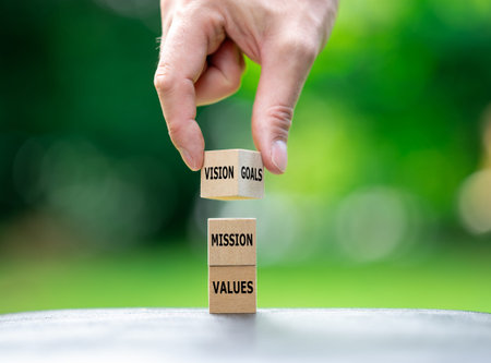 A stack of wooden cubes as well as the words values, mission, vision and goals.