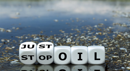 Dice form the expression 'just stop oil' in front of a lake full of oil.の素材