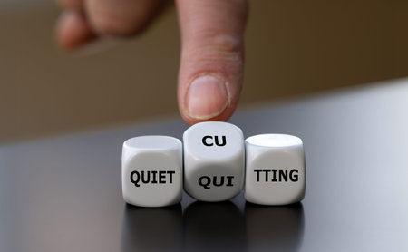 Hand turns dice and changes the expression 'quiet quitting' to 'quiet cutting'.