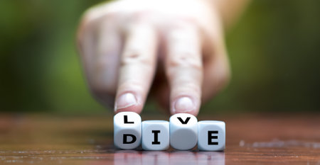 Hand turns dice and changes the word die to live.の写真素材
