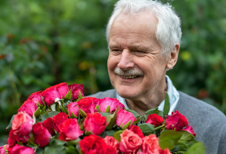 Senior man with a roses bouquet. Symbol for a date at an older age.の写真素材
