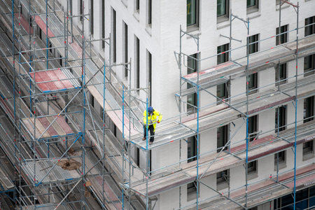 Construction worker removes scaffolding of a new building.