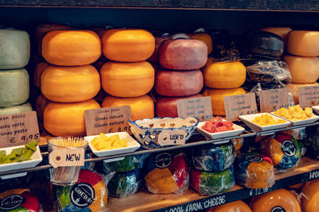 Gouda, Netherlands - July 20, 2020: many different kinds of large delicious hunks of cheese on the shelves on sale in a Cheese shop in Goudaのeditorial素材