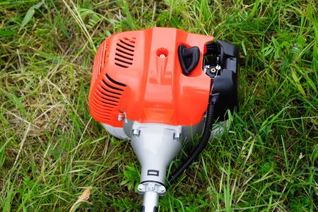 The engine of a gas trimmer lies on the grass. Power part of the trimmer. Trimer gascosis with a leaf for mowing grass and shrubs.の写真素材