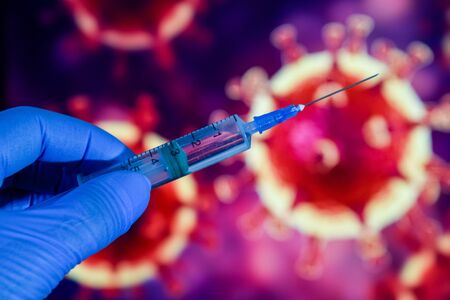 Coronavirus vaccine. A hand in medical gloves holds a vaccine and a syringe against the background of the image of a coronavirus. covid-19,の写真素材