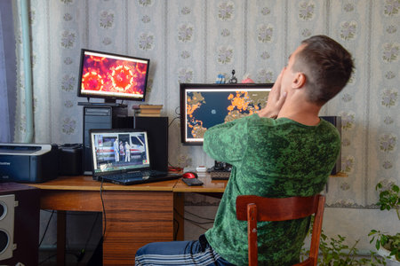 Krasnodar, Russia - April 02, 2020: A man sits at computer monitors and is horrified by the news...