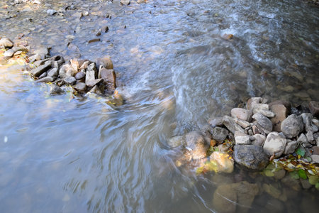 The flow of water on the doorstep in a mountain river. A shallow mountain river, the bottom of a...