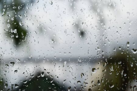 Raindrops on the window pane. Blurred background outside the window in the rain.