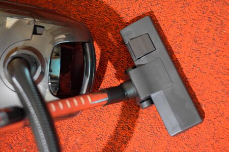 A vacuum cleaner with a set of brushes and bags. A vacuum cleaner on the red carpet.の写真素材