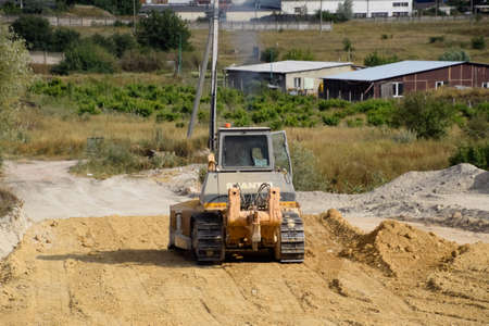 Taman, Russia - July 9, 2019: Excavator on the construction of the road. Heavy machinery for construction.のeditorial素材