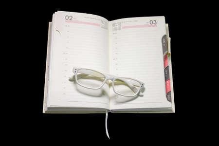 glasses on diary notebook in isolated