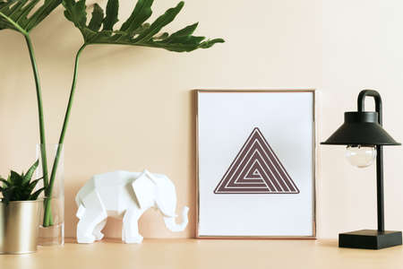 The creative workspace with leafs, elephant, plant, lamp and poster frame. Modern colorful office...