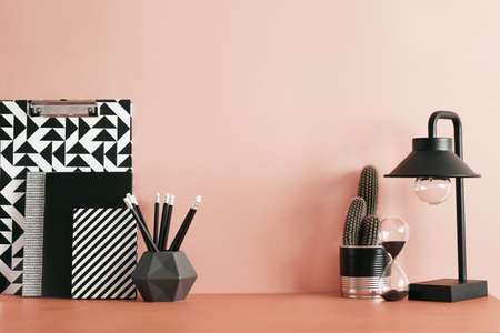 Red pastel desk with cacti, office accessories, sticky notes and lamp. Creative workspace with red...