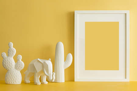 The design yellow desk with cacti, elephant and frame. Modern mock up concept.