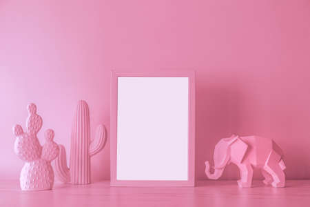 The design pink desk with cacti, elephant figure and photo frame. Modern mock up concept and...