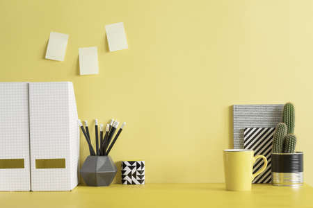 Yellow desk with cacti, office accessories, sticky notes and lamp. Creative workspace with yellow...