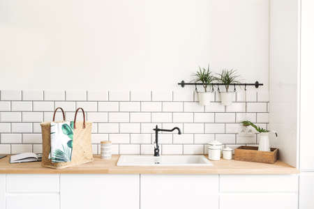 Modern and design scandinavian kitchen with plants, accessories and straw bag. Sunny and bright space with white brick wall.の写真素材