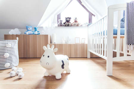 Modern scandinavian nursery interior with toys, teddy bears, baby cot and cotton lamps. Sunny and...