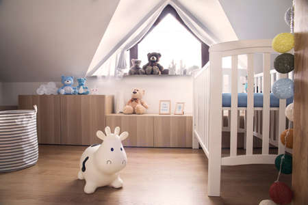 Modern scandinavian nursery interior with toys, teddy bears, baby cot and cotton bowls lamps. Sunny and bright room.の写真素材