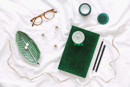 Trendy and stylish flat lay with woman accessories, green notebook, glasses, and candles. Lifestyle, influencer and blogger concept.の写真素材