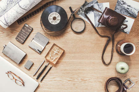Stylish composition of flat lay on wooden desk with succulent, map, cup of coffee, croissant, phone, notebook, camera and office accessories. Creative desk of freelancer. Copy space for inscription.の写真素材
