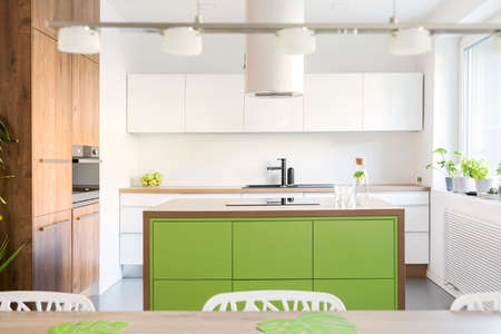 Modern and design scandinavian space with kitchen island, table and accessories. Sunny and bright kitchen with white white wall. Stylish accessories.の写真素材