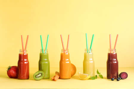 Composition of healthy and useful colorful vegetable juices and smoothies with chia and flax seeds in glass bottles, set on the yellow background, copy spaceの写真素材