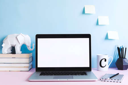 Stylish and modern desk with laptop mock up screen, books, elephant figures, office accessories and...