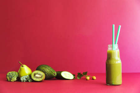 Healthy detox smoothie with green vegetables and fruit lie on the red table. Copy space, red backgrounds wall.の写真素材