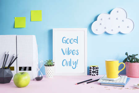 Stylish and modern workspace with mock up poster frame, office accessories, memo sticks, cup of coffee, notebooks and cloud. Design space of home office.の写真素材