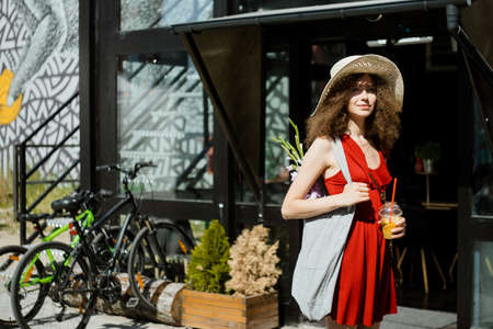 Summer sunny lifestyle portrait of young beautiful woman walking on the street market, wearing cute...