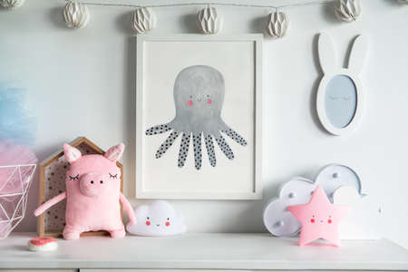 Stylish scandinavian nursery interior with mock up photo frame , pinky pig, toys and star. Hanging cotton lamps and mirror on the white background wall.の写真素材