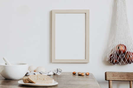 Vintage kitchen interior with mock up photo frame, straw basket, natural bread and bag with apples. Minimalist concept of kitchen space.の写真素材