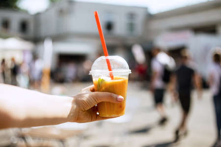 Close up of summer juice with orange and mint in local restaurant. Beautiful woman drinking tasty smoothie, smiling enjoy her weekends, holiday.の写真素材
