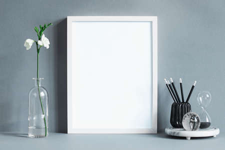 Minimalistic composition of mock up photo frame with flower leaf in vase, office accessories and...