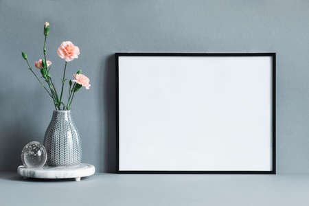 Stylish and minimalistic composition of mock up photo frame with flowers in vase. Modern concept of...