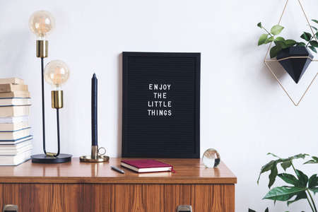 The retro mock up photo frame on the vintage wooden shelf , hanging plant in design pot, books, gold pyramid and table lamp. Concept of minimalistic shelfie.の写真素材