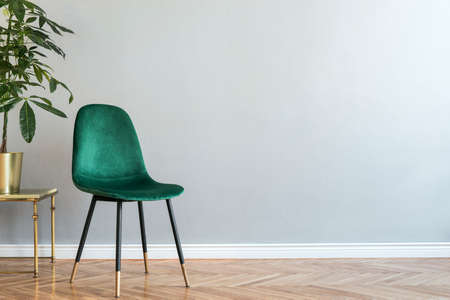 Luxury and minimalistic grey home interior with green velvet chair, table with plant. Copy space for inscription, mock up poster. Empty wall. Brown wooden parquet.の写真素材