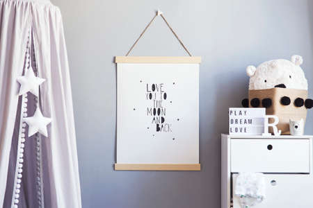 Stylish scandinavian nursery interior with hanging mock up poster, grey canopy with stars and white shelf with teddy bear in the natural basket and children's accessories. Grey background wall.の写真素材