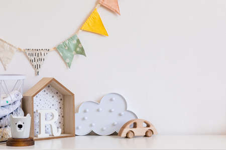 Stylish and cozy childroom with wooden toys, cloud and hanging cotton flags. Modern scanidnavian interior with white background wall. Copy space for inscription or product. Real phote. Template.の写真素材