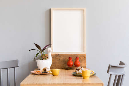 Stylish and cozy interior of kitchen space with wooden table with mock up photo frame, beautiful...