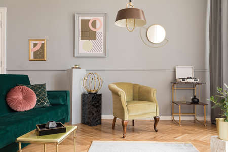 Stylish and luxury living room of apartment interior with elegant green velvet armchair and sofa,...